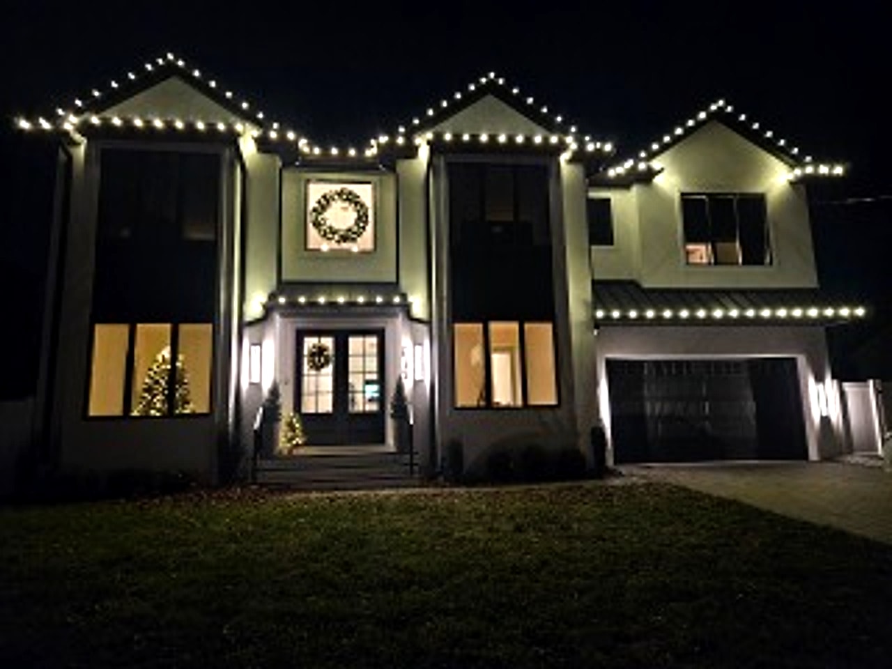 Warm white C9 LED holiday roofline lighting installed on a modern home in Bergen County, NJ