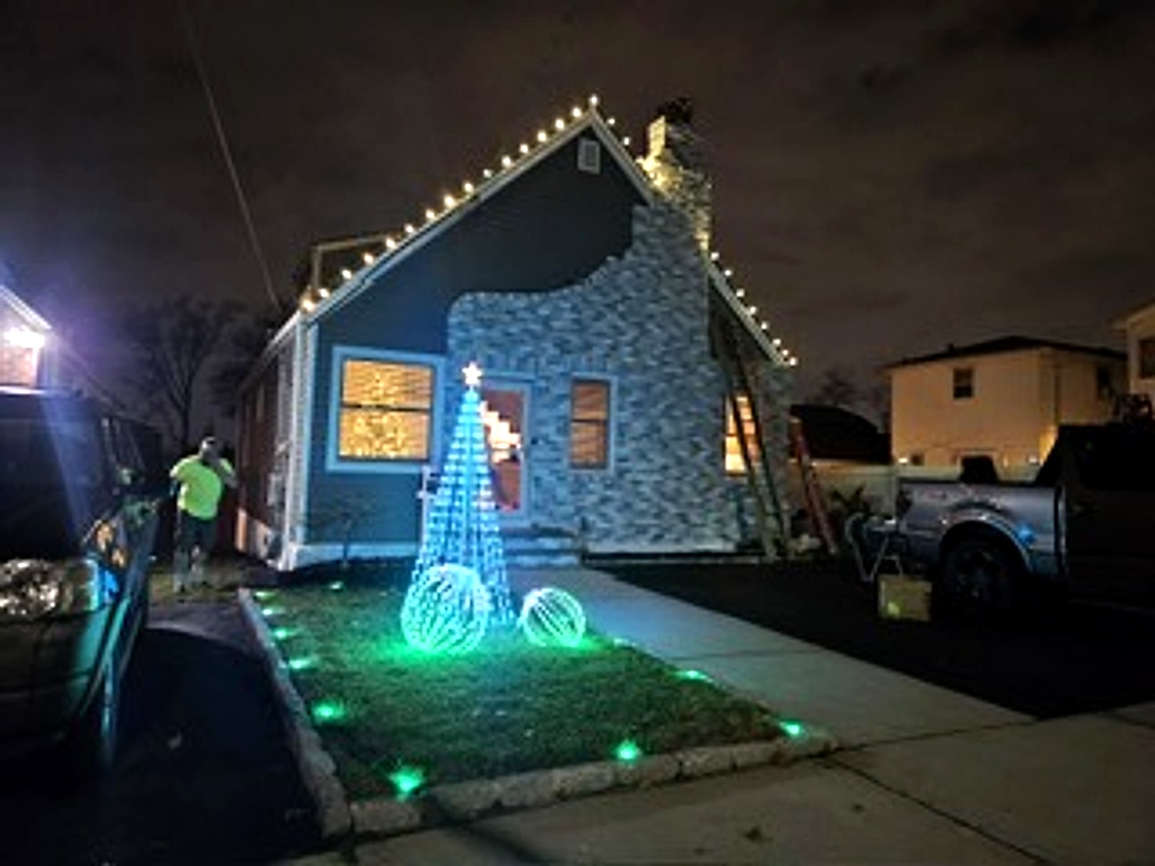 Lights & Ladders crew member installing warm white holiday roofline lighting on-site