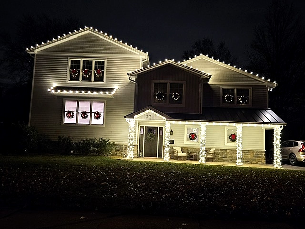 Warm white holiday lighting wrapped around entry columns and portico at a Bergen County, NJ home